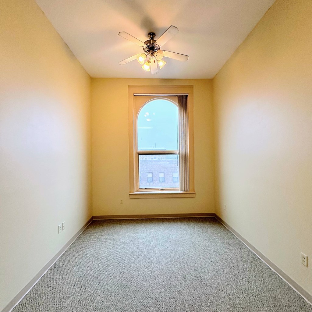 an empty room with a window and a ceiling fan