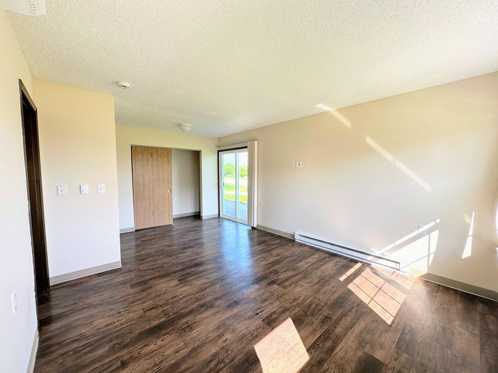 an empty living room with wood floors and white walls