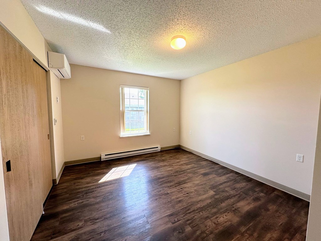 an empty living room with wood flooring and a window