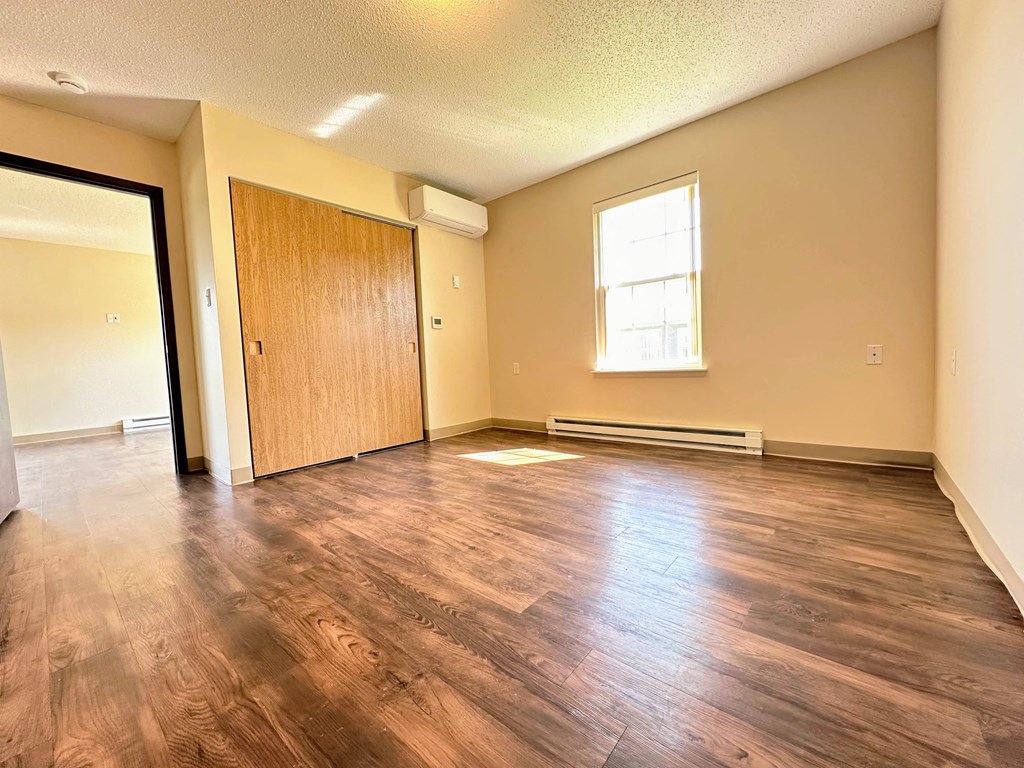an empty living room with wood flooring and a door