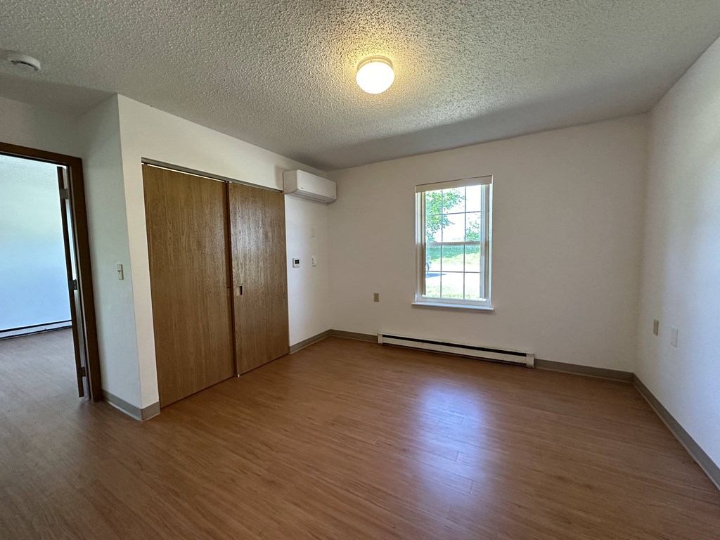 an empty living room with wood flooring and a window