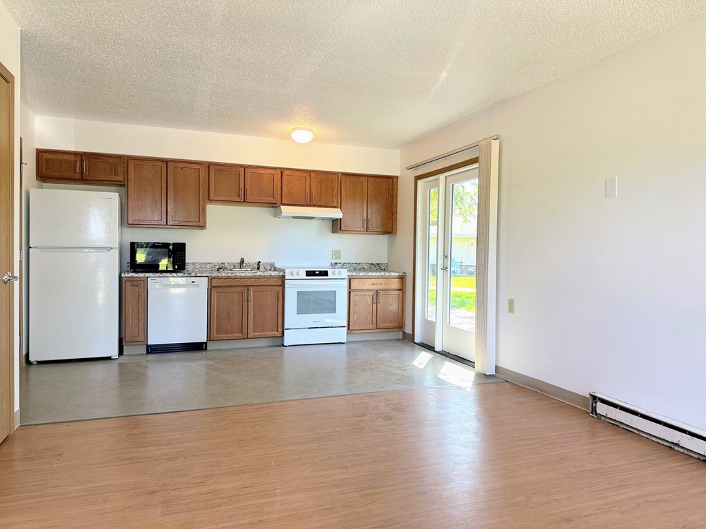 an empty kitchen with white appliances and wooden cabinets
