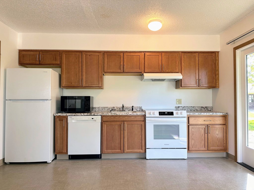 an empty kitchen with white appliances and wooden cabinets
