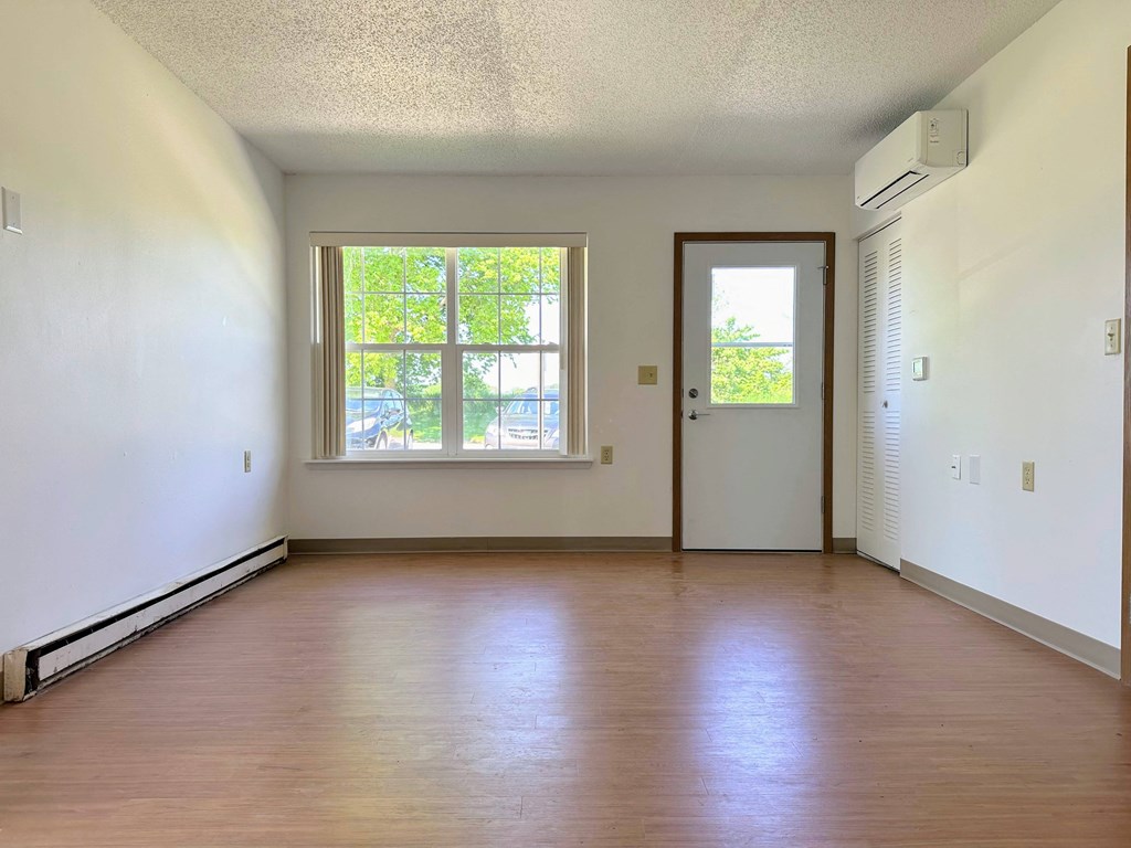 an empty living room with wood floors and a window