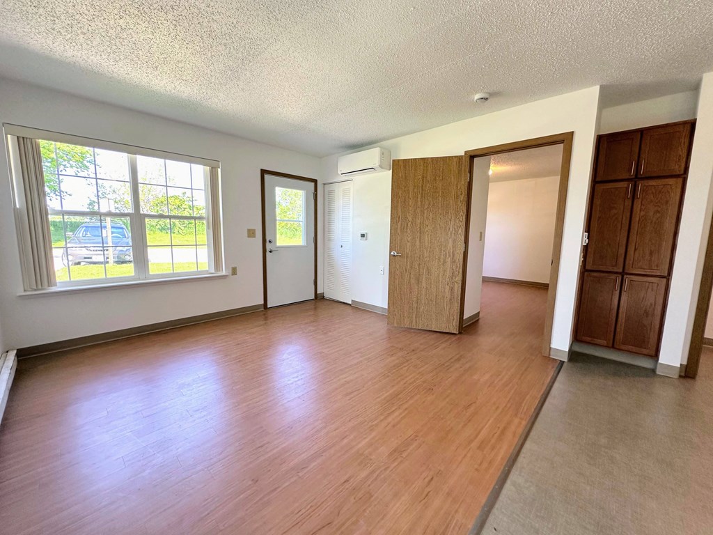 an empty living room with wood flooring and a window