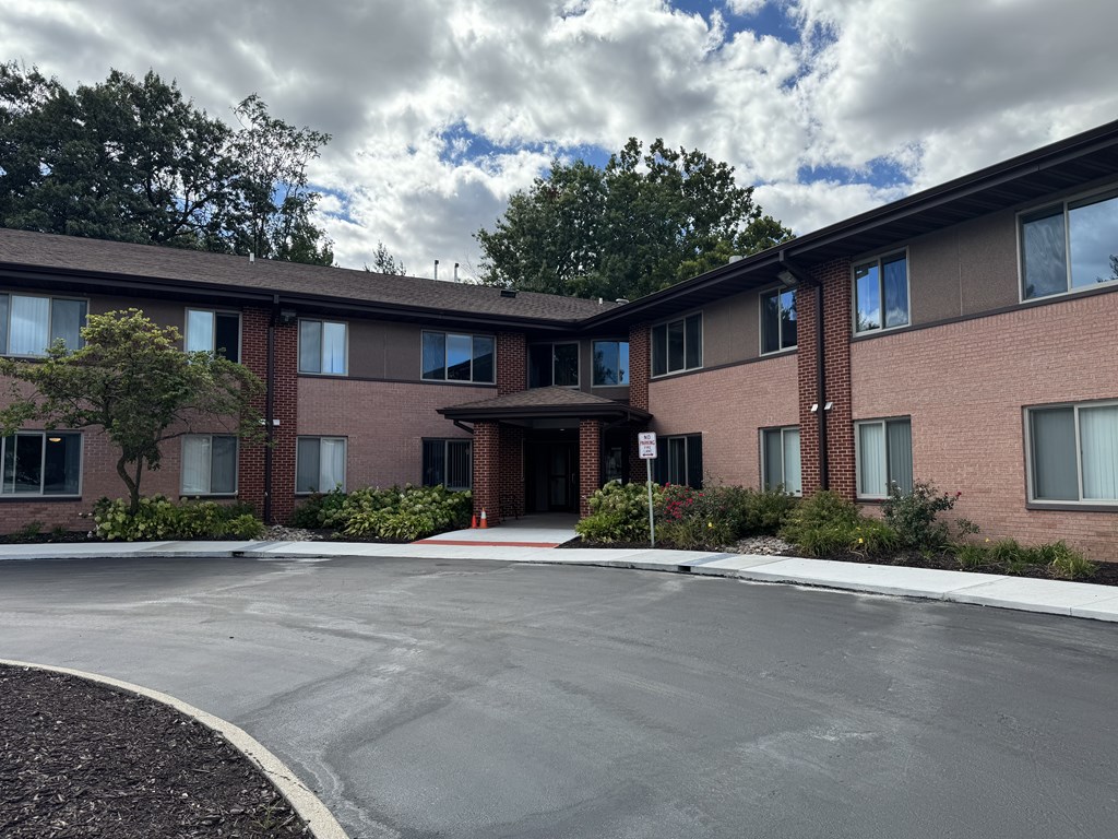 A building with a red brick exterior and a parking lot in front.