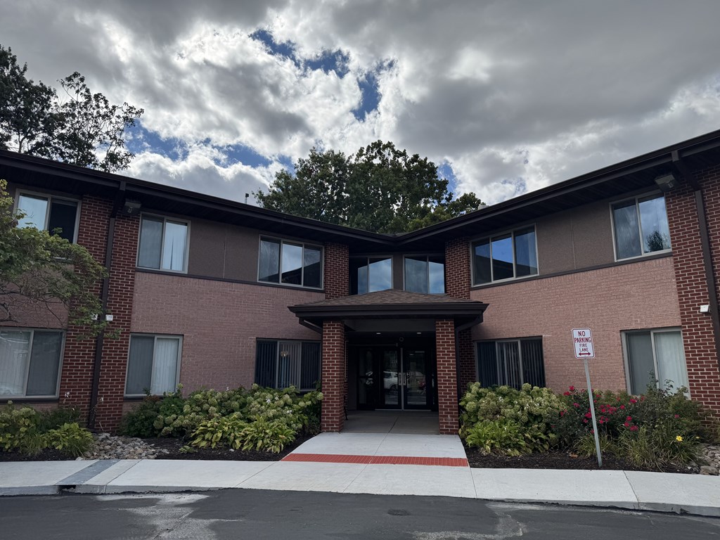 A building with a red brick facade and a white sign in front.