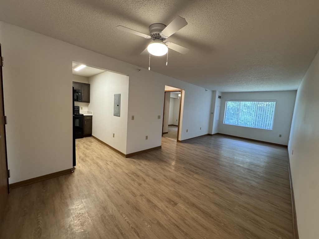 A room with a ceiling fan and wooden flooring.