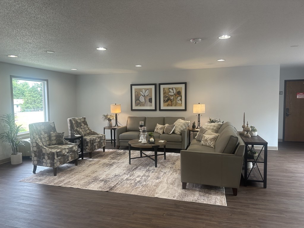 A living room with a grey couch, two chairs, a coffee table, and two framed pictures on the wall.