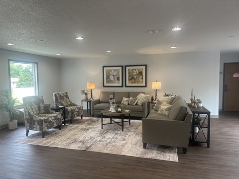 A living room with a grey couch, two chairs, a coffee table, and two framed pictures on the wall.
