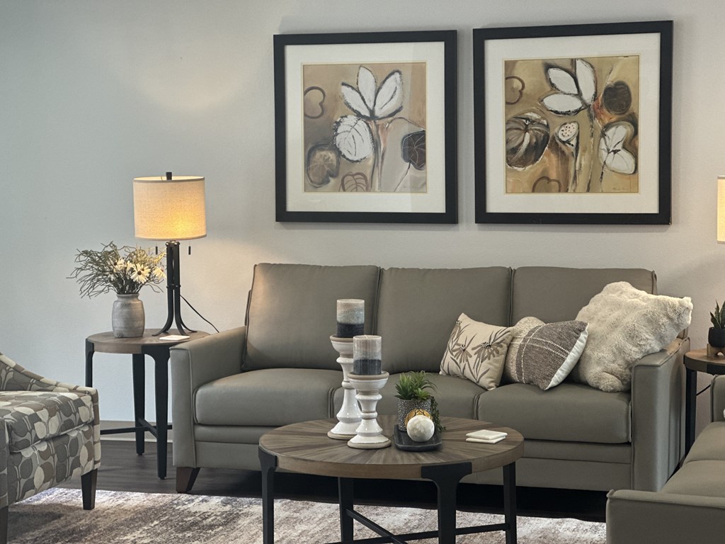 A living room with a grey couch, a coffee table, and two framed pictures on the wall.