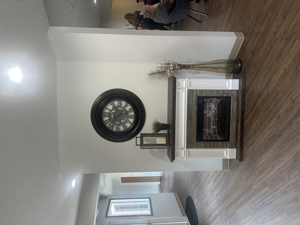 A clock hangs on a wall above a fireplace in a room.