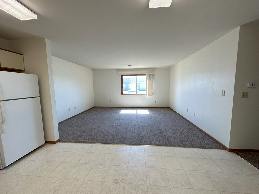 a living room with a refrigerator and a window