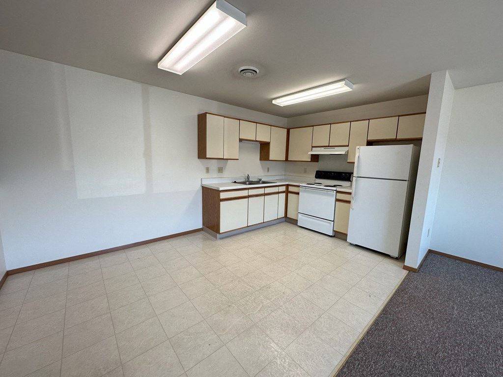 a kitchen with a white refrigerator freezer next to a stove top oven
