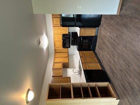 A kitchen with wooden drawers and a black fridge.