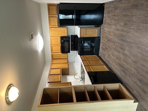 A modern kitchen with wooden drawers and black appliances.