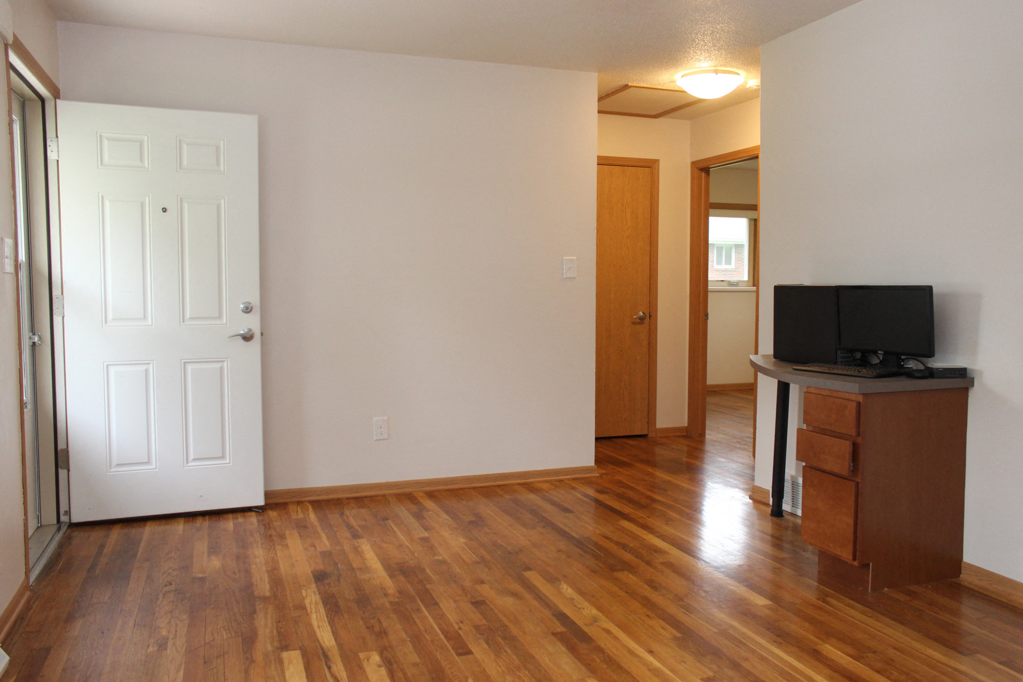 A room with a white door, a brown cabinet, and a wooden floor.