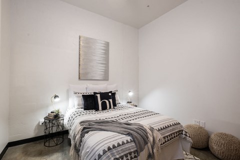 A bedroom with a bed, a lamp, and a wall hanging.