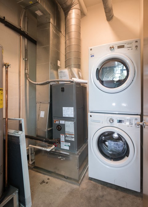 A washing machine is on top of a dryer in a utility room.