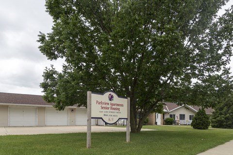 A sign for Parkview Apartments Senior Housing stands in front of a building.