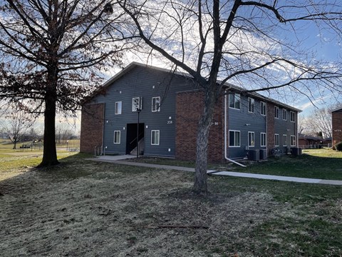A grey building with a tree in front of it.