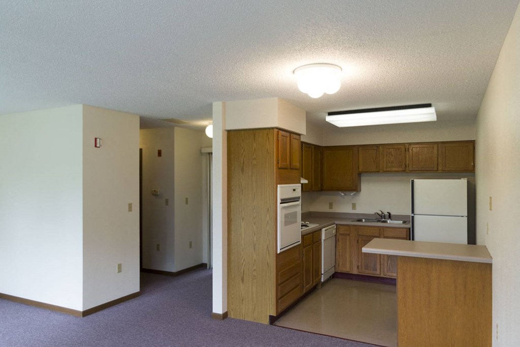 an empty kitchen with white appliances and wooden cabinets