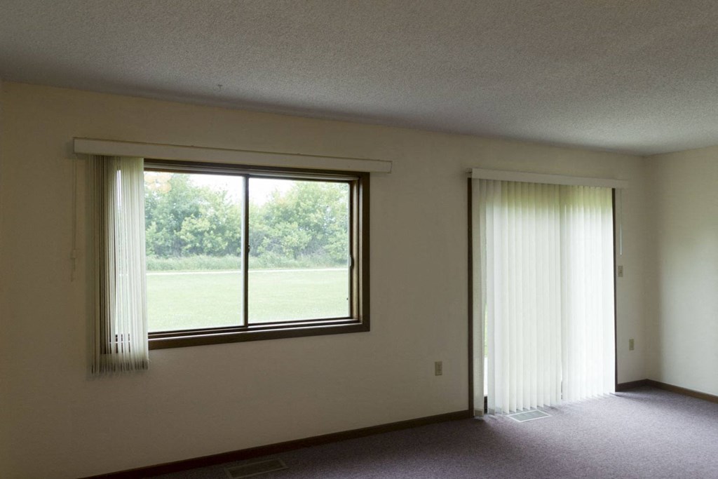 an empty living room with a large window and curtains