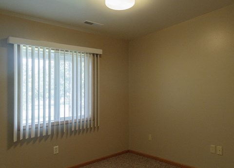A room with a window covered by white blinds.