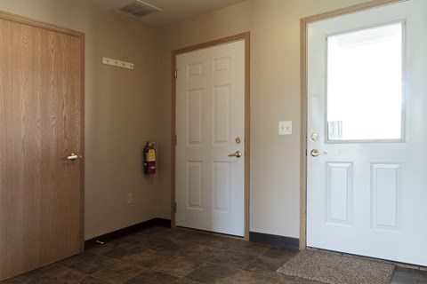A hallway with a brown door on the left and two white doors on the right.