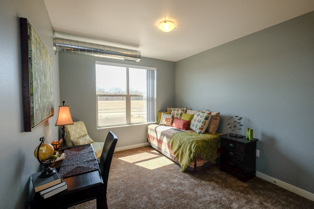 A bedroom with a bed, a chair, and a desk.
