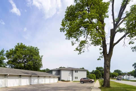 A large white building with a grey roof and a tree in front of it.