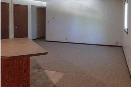 an empty living room with a table in the center