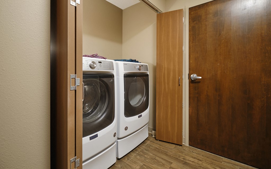 a washer and dryer in a laundry room with a wooden door