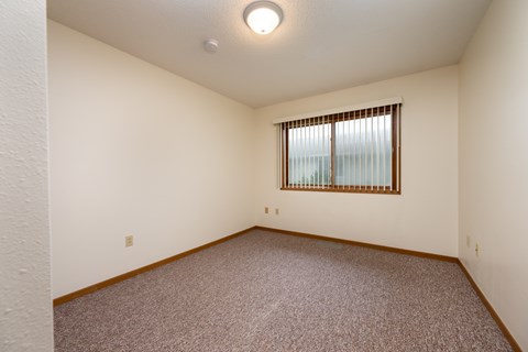 A room with a window and carpeted floor.