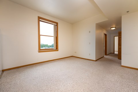 A room with a window and carpeted floor.
