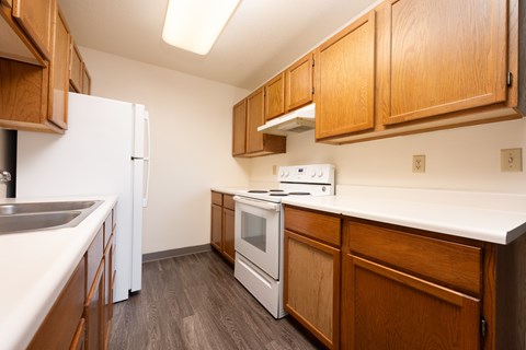 A kitchen with white appliances and wooden cabinets.