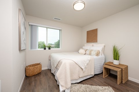 A bedroom with a bed, a small table, and a window.