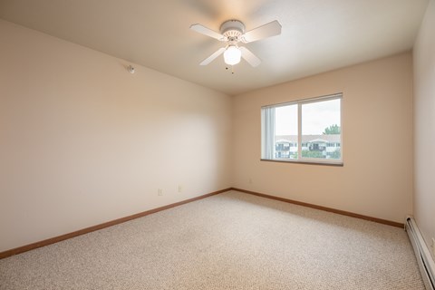 A room with a ceiling fan and a window.