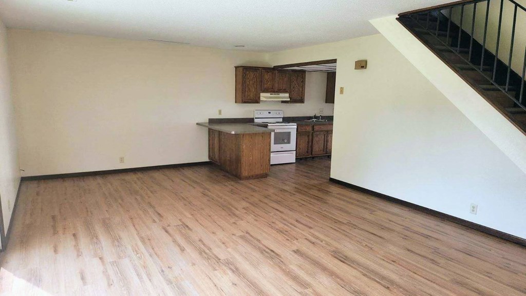 an empty kitchen with wooden floors and white walls