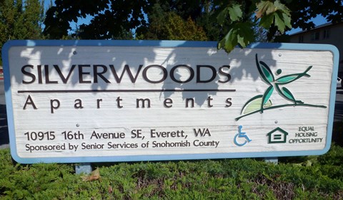 a sign for silverwoods apartments is shown in the grass
