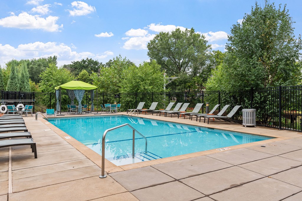 a swimming pool with chairs around it and trees in the background at Be @ Axon Green, Minnesota, 55416