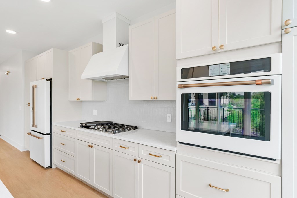 A white kitchen with a black stove top and a white oven with a window.