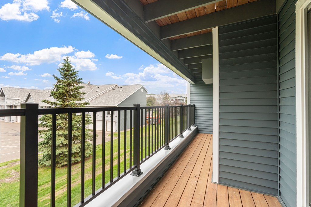 A balcony with a black railing and a wooden floor.