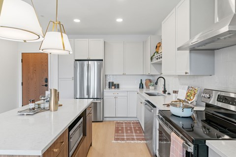 A modern kitchen with white cabinets and a marble countertop.