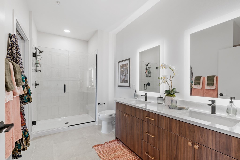 A bathroom with a double-vanity and walk-in shower in a one-bedroom, one-bathroom apartment home at Lilia in Lilydale, MN 55118