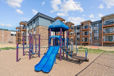 A playground with a blue slide and a purple structure.