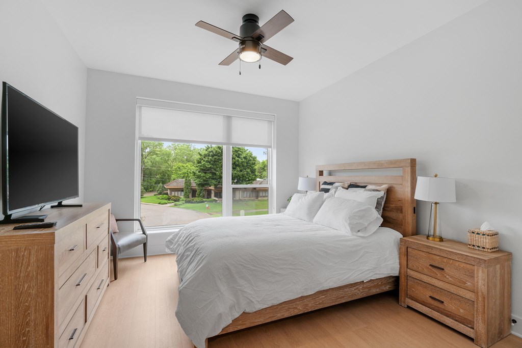 A queen bed, armoire, and TV in the Guest Suite, a reservable community amenity at Lilia in Lilydale, MN 55118