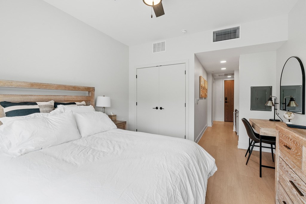 A queen bed, armoire, TV, and kitchenette in the Guest Suite, a reservable community amenity at Lilia in Lilydale, MN 55118. This room also features in-unit laundry and a bathroom.