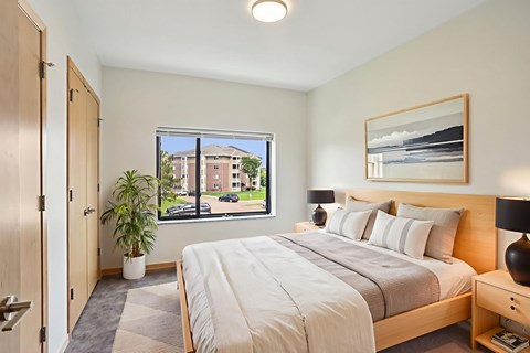 A bedroom with a large bed and a window overlooking a street.