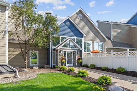 A house with a blue trim and a white picket fence.
